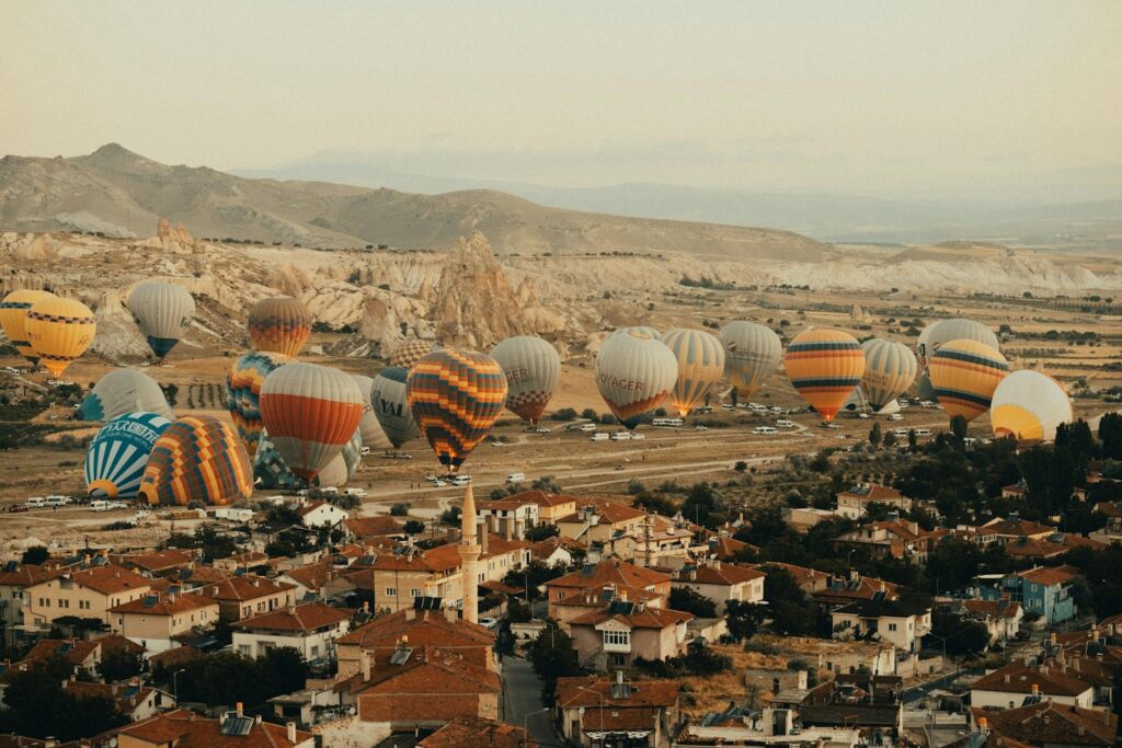 A scenic view of vibrant hot air balloons hovering over the unique rocky landscape of Cappadocia.