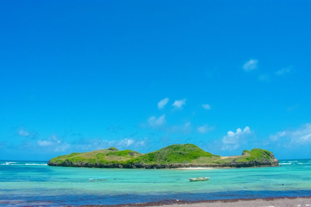 green island on blue sea under blue sky during daytime